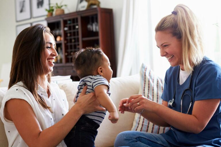 Two moms talking and playing with baby